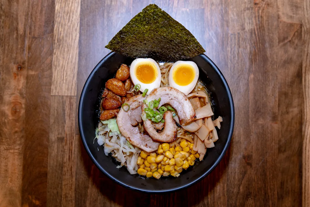 Ramen topped with nori, chashu pork, corn, cabbage and a halved soft-boiled egg