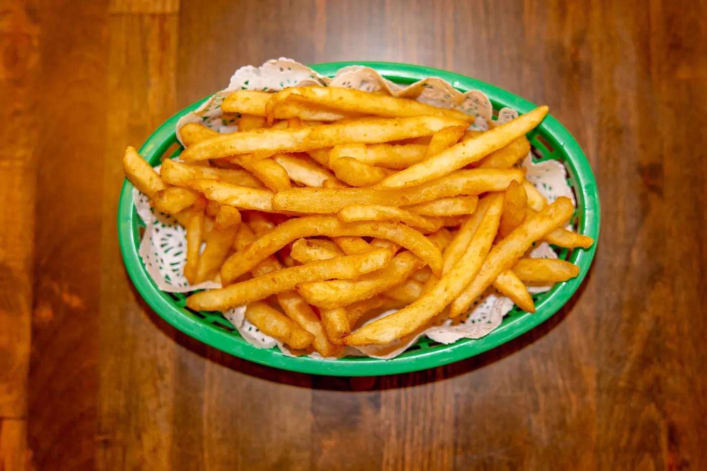 A basket of golden french fries on a paper doily