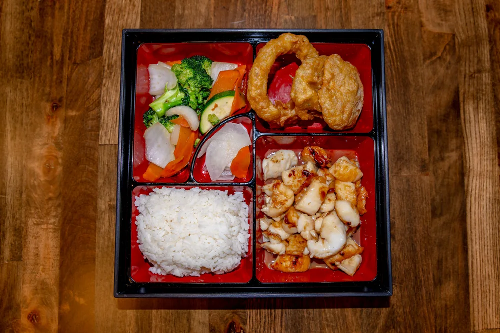 Bento box with seared scallops, rice, fried squid rings and stir-fried vegetables