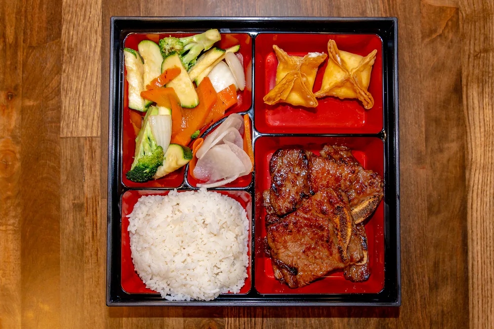 Bento box with grilled short rib, rice, crab rangoon and stir-fried vegetables