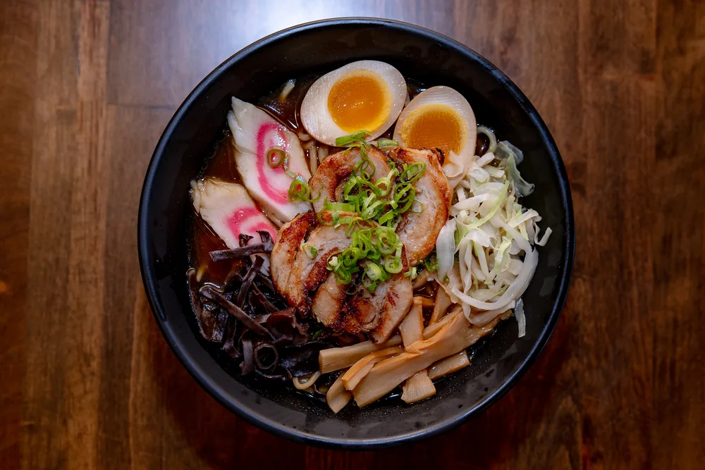 Ramen in a clear soy broth with chashu pork, soft-boiled egg, narutomaki, bamboo and cabbage